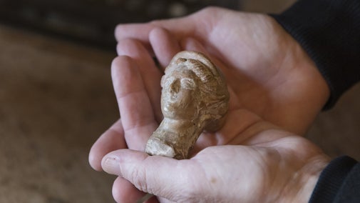 The head of an ancient Greek statue of Demeter is held in a pair of hands
